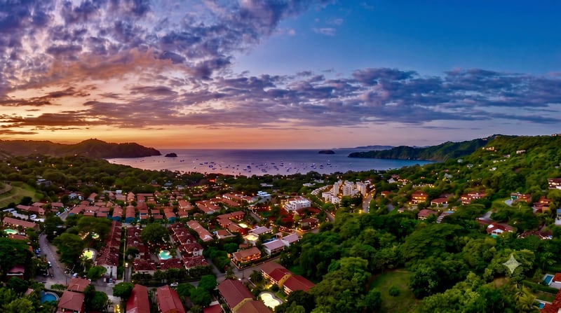 Aerial view over Playas del Coco at dusk, the bay full of moored boats and the town lit below
