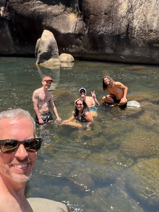 Friends swimming in a clear river swimming hole between granite boulders