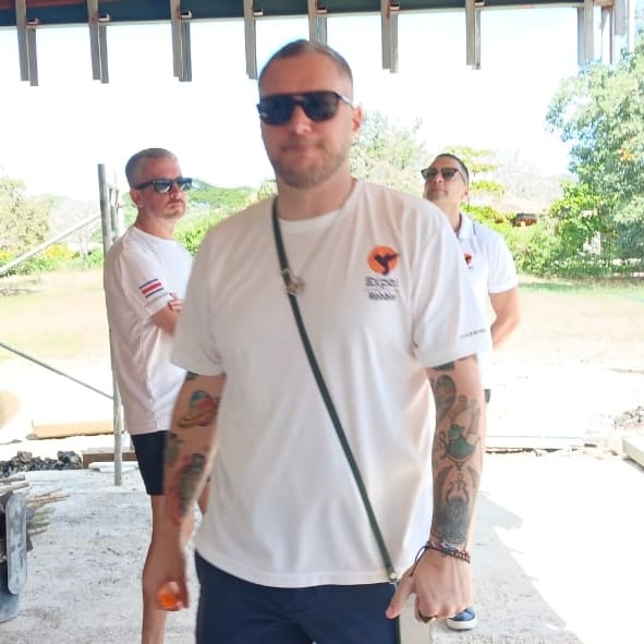 Walking through an open-sided building on a site visit with two colleagues in company polo shirts