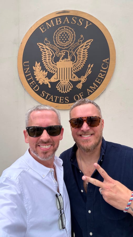 The two of us in sunglasses beside the United States Embassy seal